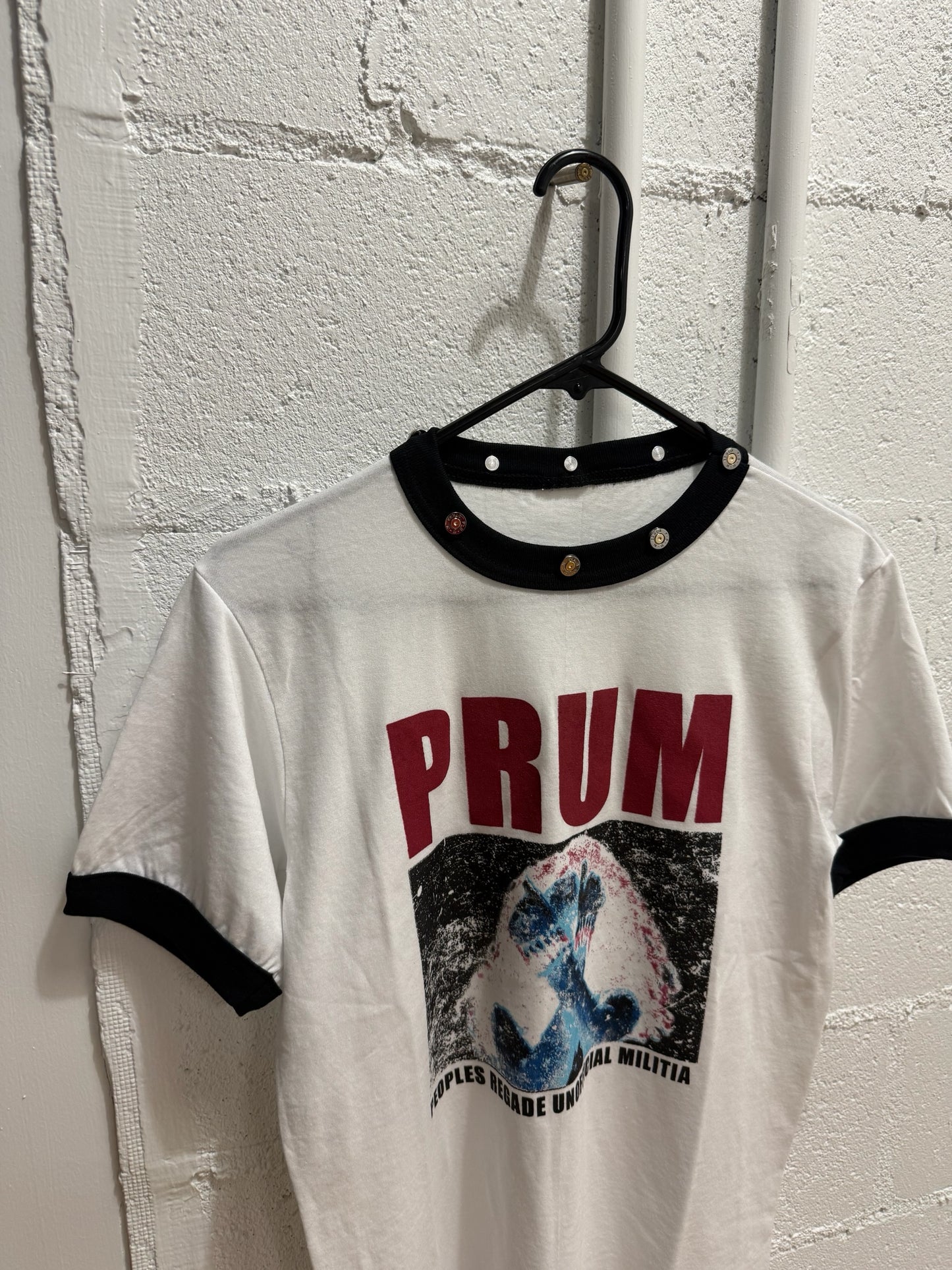 prum.online white cotton ringer t-shirt with black ribbed collar, metallic stud hardware, and distressed graphic print